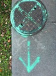 Manhole cover with spray paint markings.