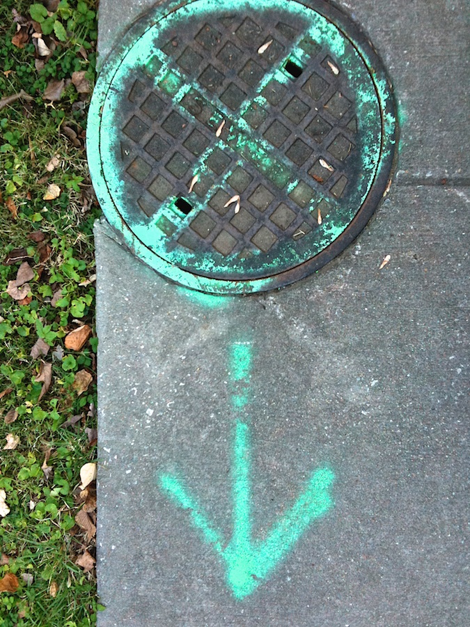 Manhole cover with spray paint markings.