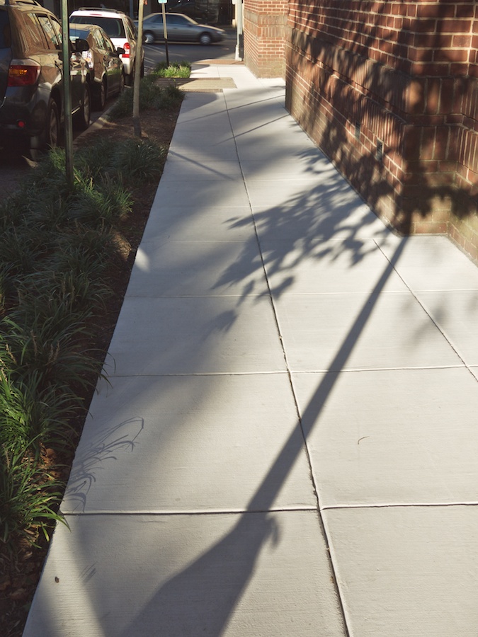 Shadows and reflections on sidewalk pavement.