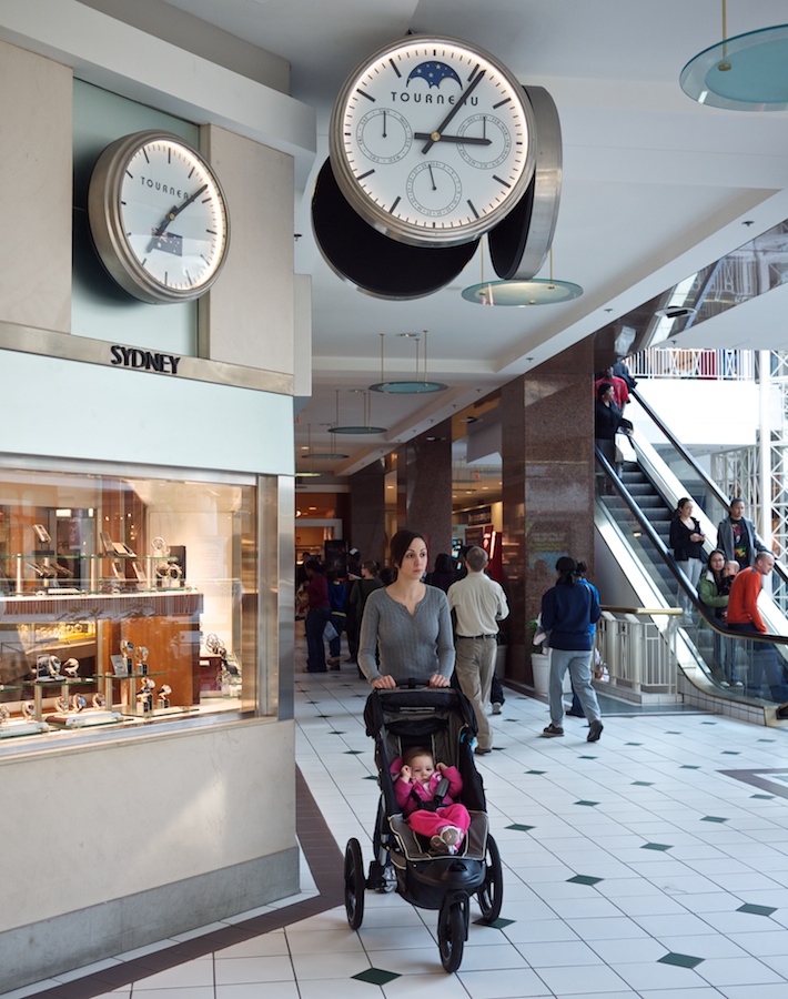 Woman pushing stroller in mall.