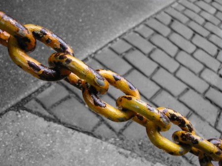 Rusty yellow chain against pavement