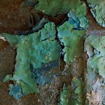 Flaking layers of blue and green paint on a fire hydrant.