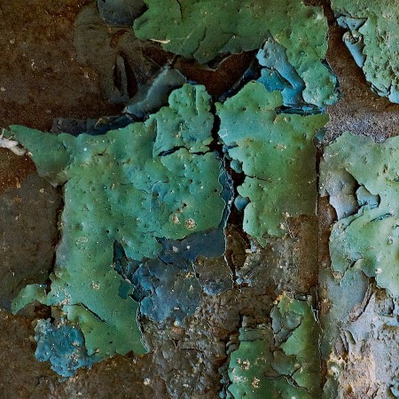 Flaking layers of blue and green paint on a fire hydrant.