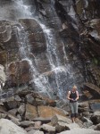 Woman collecting stones below waterfall.