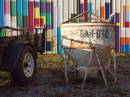 Vehicle, rusted hopper, painted siding.